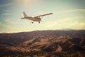 Small single engine airplane flying in the gorgeous sunset sky above the spectacular mountains Royalty Free Stock Photo