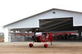 Small single prop engine plane parked in front of workshop hangar