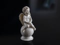 Small, sitting, plaster angel with wings, on a black background Royalty Free Stock Photo