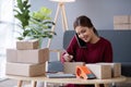 A small SME business owner receives product orders and writes shipping information on cardboard boxes in the home office Royalty Free Stock Photo