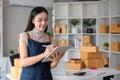 A small SME business owner receives product orders and writes shipping information on cardboard boxes in the home office Royalty Free Stock Photo