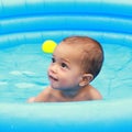 Amazed cute baby boy in blue inflating pool