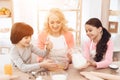 Small smiling boy is whipping eggs in bowl with his sister and young grandmother Royalty Free Stock Photo