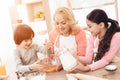 Small smiling boy is whipping eggs in bowl with his sister and young grandmother Royalty Free Stock Photo