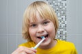 Little child brushing teeth with electric toothbrush in bathroom Royalty Free Stock Photo