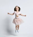 Small smiling cute girl in casual summer dress and sneakers jumping over white wall background Royalty Free Stock Photo