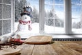 Small smiling snowman in a hat and scarf with white snowy winter background. Space for decorations on christmas background. Royalty Free Stock Photo