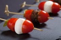 Small snacks canape with cherry tomatoes, mozzarella and meatbolls on skewer on a black slate plate. Shallow depth of field