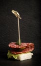 Small snacks canape with salami, bread and lettuce on skewer on Royalty Free Stock Photo