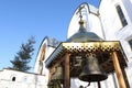 Small snow-covered bell tower with silver bells on the background of the Orthodox Church. Winter  Christmas. Royalty Free Stock Photo