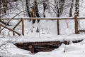 Small, snow-covered wooden bridge, across a forest stream, in a city park Royalty Free Stock Photo