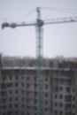 Small snow falls on the background of blurred tower crane and snow-covered construction