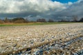 Small snow on a plowed field and cloudy sky Royalty Free Stock Photo