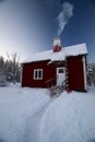 Small snowbound house in northern Sweden with smoking chimney Royalty Free Stock Photo