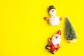 Small snowman and Small Santa Claus on yellow background at Christmas day.Theme Christmas day background.