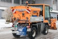 Small snowplow removing snow from street and sprinkled salt ant