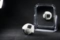 Small soccer ball toy in front of a mirror on a black background