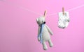 Small socks and toy bear hanging on washing line against color background. Baby accessories Royalty Free Stock Photo