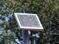 Small solar panel on pole with trees