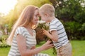 Small son gives his mother a bouquet of delicate flowers.