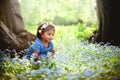 A small Asian girl is sitting on field of forget me not blue flowers Royalty Free Stock Photo