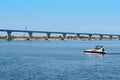 A small speedboat floats along the river against the backdrop of a bridge under construction. Royalty Free Stock Photo