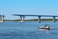 A small speedboat floats along the river against the backdrop of a bridge under construction. Royalty Free Stock Photo