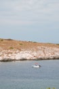 a small speedboat is on the water next to a rocky island Royalty Free Stock Photo