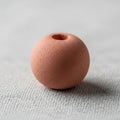 Spherical terracotta colored object resembling a bead with a central Royalty Free Stock Photo