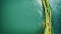 A small spit with a path covered with green grass on both sides, on a clear lake. Aerial photography