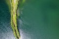 A small spit with a path covered with green grass on both sides, on a clear lake. Aerial photography