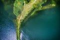 A small spit with a path covered with green grass on both sides, on a clear lake. Aerial photography