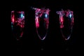 Small splashes of clear liquid glowing in red with blue highlights in three glasses in a row on a black background Royalty Free Stock Photo