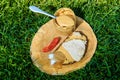 Spoonful of peanut butter on wooden plate with meat sandwich