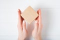 Small square cardboard box in female hands. Top view, white background