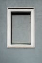 Small square window with white frame set in smooth gray plaster wall, minimalist architectural detail with clean geometry and Royalty Free Stock Photo