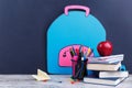 A stack of books, stationery and a apple, on a background with an image of a paper backpack. The concept of education.