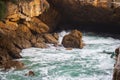 Small statue on seacoast in evening sunlight. Rocky cave in coast of Atlantic Ocean. Coastal nature. Cantabria landscape at sunset Royalty Free Stock Photo