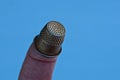 Small steel thimble on finger on blue background Royalty Free Stock Photo