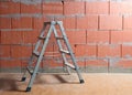 Small step ladder in front of a raw brick wall from Porotherm style clay blocks in an unfinished new building, copy space