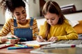 Small Steps. Caucasian little girl spending time with african american baby sitter. Kid is drawing, learning how to draw Royalty Free Stock Photo