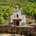 Small stone chapel next to ancient stone wall in the green field. Asturias Spain Royalty Free Stock Photo