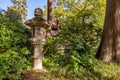 Small stone lantern in a peaceful Japanese garden silhouetted against a backdrop of lush greenery