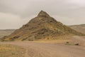 A small stone mountain at the intersection of two roads in the desert in southeastern Kazakhstan