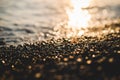 Small stones by the sea with bokeh effect. Blurred decorative background, place for text. Summer wallpaper, sunny sunset