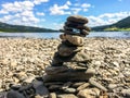 Close-up of stone cairn on a pebble beach with mountains and lake in the background