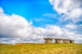 Small stony empty houses on green grass and cloudy sky