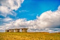 Small stony empty houses on green grass and cloudy sky