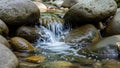 A small stream flows over smooth rounded rocks creating a gentle waterfall Royalty Free Stock Photo