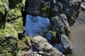 A small stream flows through a stone hole in the rock wall. Royalty Free Stock Photo